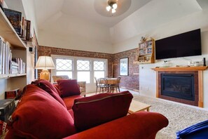 A living room with a fireplace, a television, and a bookshelf. - Modern 2BR Loft: Walk to Downtown - 30 plus day (Leadville)