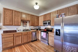 A kitchen with wooden cabinets, stainless steel appliances, and a wooden floor. - Modern 2BR Loft: Walk to Downtown - 30 plus day (Leadville)
