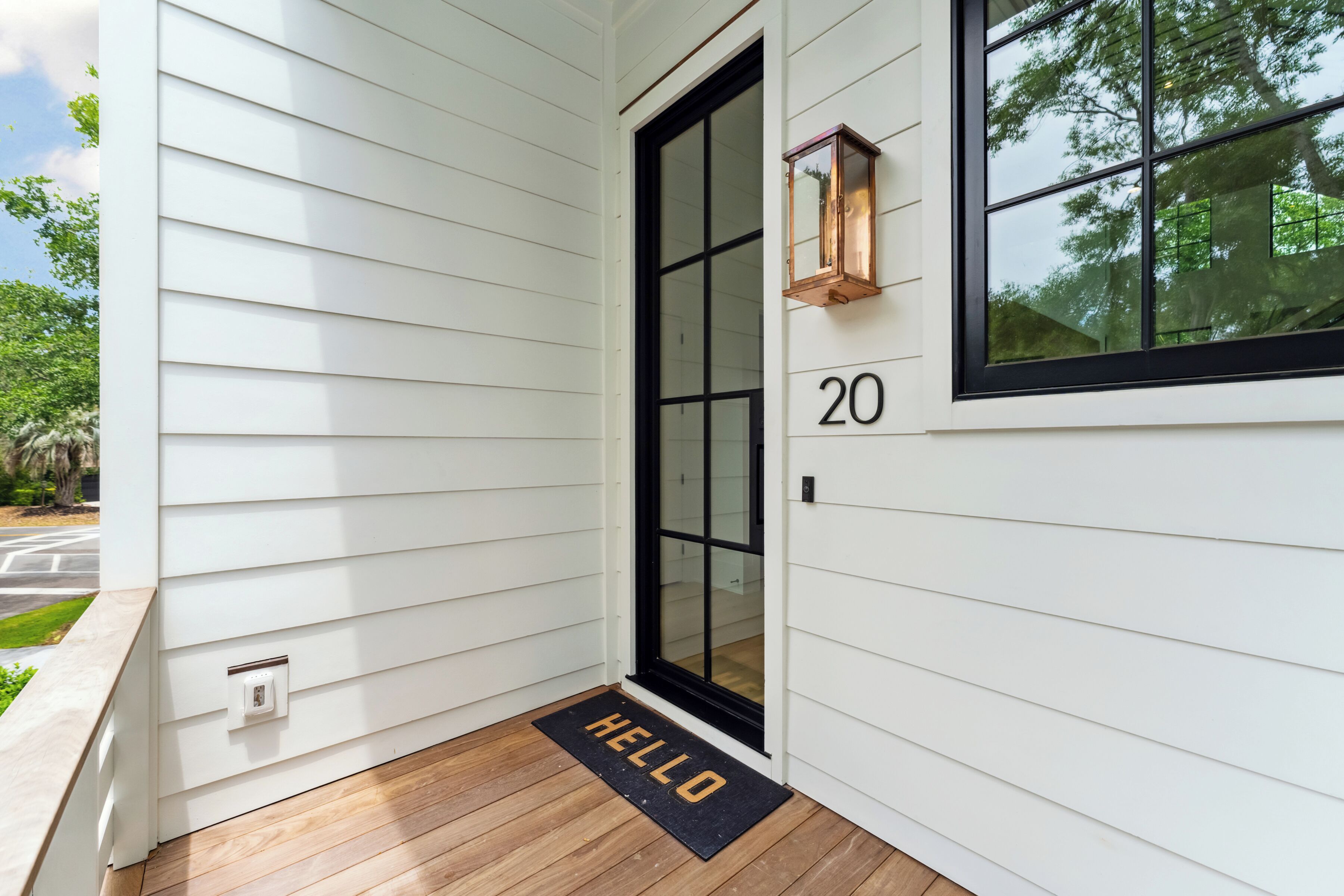 A white house with a black-framed door, a number '20' above the door, and a 'HELLO' mat at the entrance.