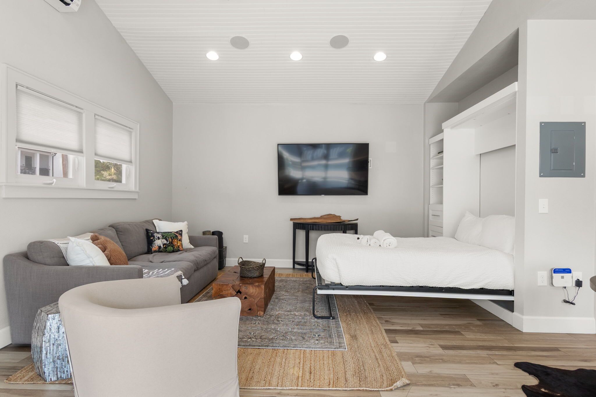Una habitación moderna y bien iluminada con una cama, un sofá, una mesa de centro y un televisor.