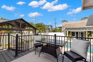 Une terrasse avec une table et des chaises, donnant sur une piscine et un quartier résidentiel.