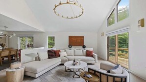 A spacious living room with a large sofa, a round coffee table, and a dining area with chairs.