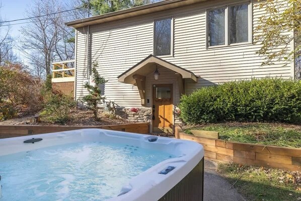 Uma casa com hidromassagem no quintal, um deck de madeira e um jardim bem cuidado.