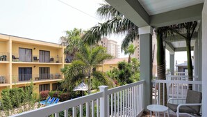 A balcony with white railings, a small round table, and two wicker chairs. - Sleeps 6 in a 4plex w Pool, Only a Block to Beach (South Padre Island)