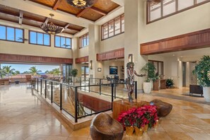 A spacious lobby with a high ceiling, large windows, and a central staircase.
