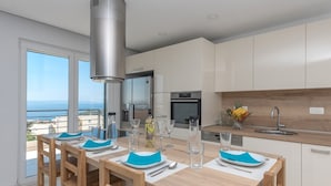 Una cucina moderna con zona pranzo, ampie finestre e vista mare.