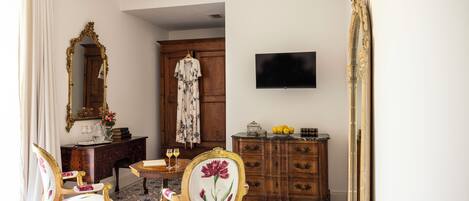 Una habitación con un aparador de madera, un televisor instalado en la pared y una silla con tapicería floral.