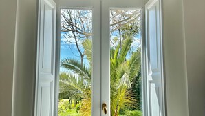 A white door with a view of a garden with palm trees and a clear sky. - Villa De Cillis Carafa (Torre del Greco)