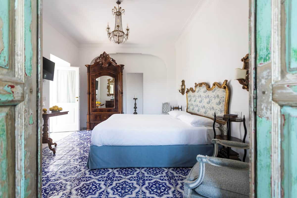 Un dormitorio con una cama grande, un aparador de madera, una silla, un espejo y una araña.