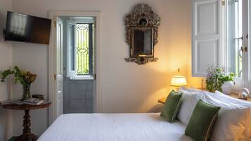 A hotel room with a bed, a television, a mirror, a lamp, and a door leading to a balcony.