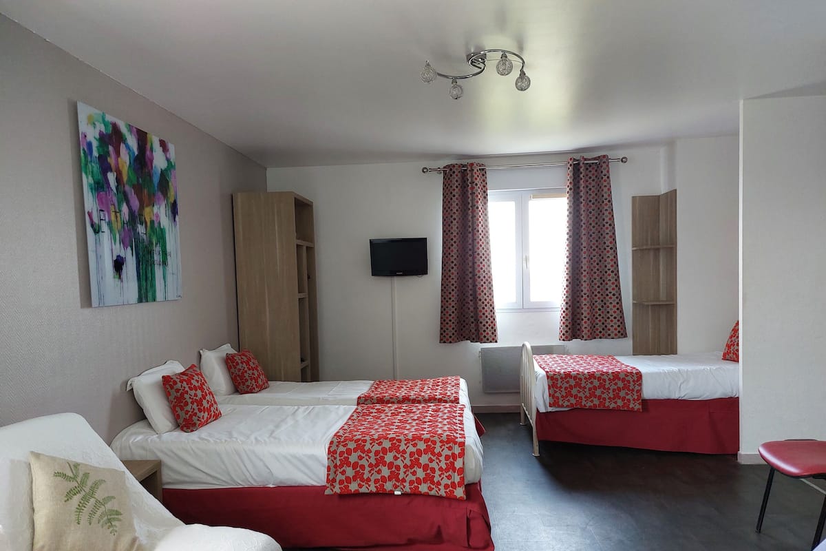 A hotel room with two beds, a TV, a window with curtains, and a painting on the wall.