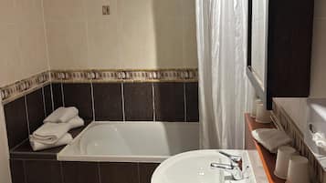Une salle de bain avec une baignoire, un lavabo, des toilettes et un rideau de douche.