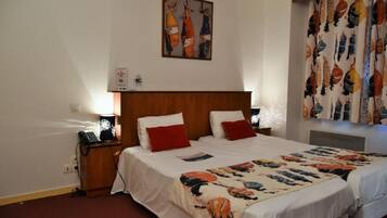 Quarto de hotel com cabeceira de madeira, duas camas com roupa de cama branca e vermelha, um quadro abstrato colorido na parede e cortina estampada.