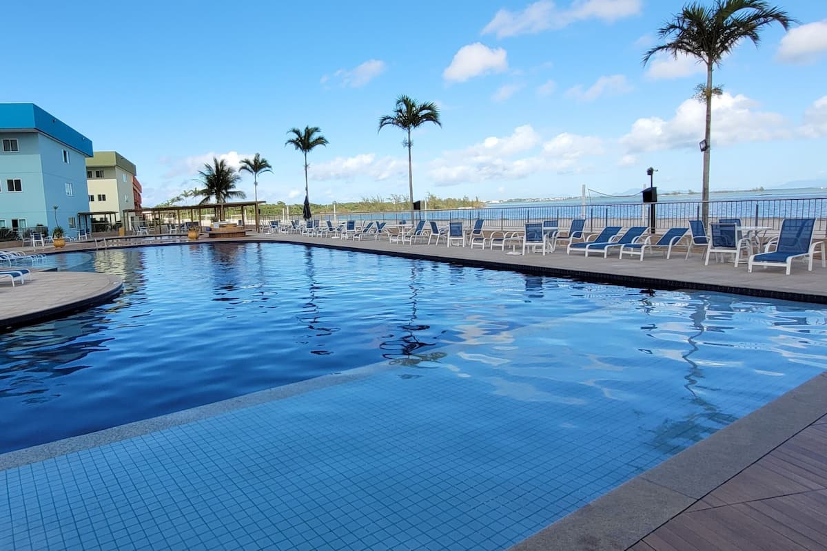 Ein Swimmingpool mit Liegestühlen und Palmen, umgeben von Gebäuden mit Balkonen.