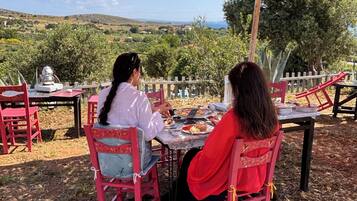 Deux personnes dînent à une table en plein air, avec vue sur un paysage vallonné.
