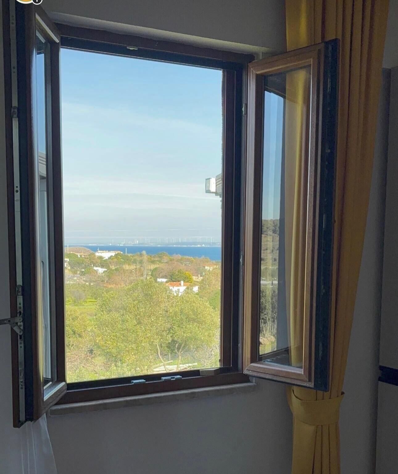 Janela com vista para uma ponte e vegetação.