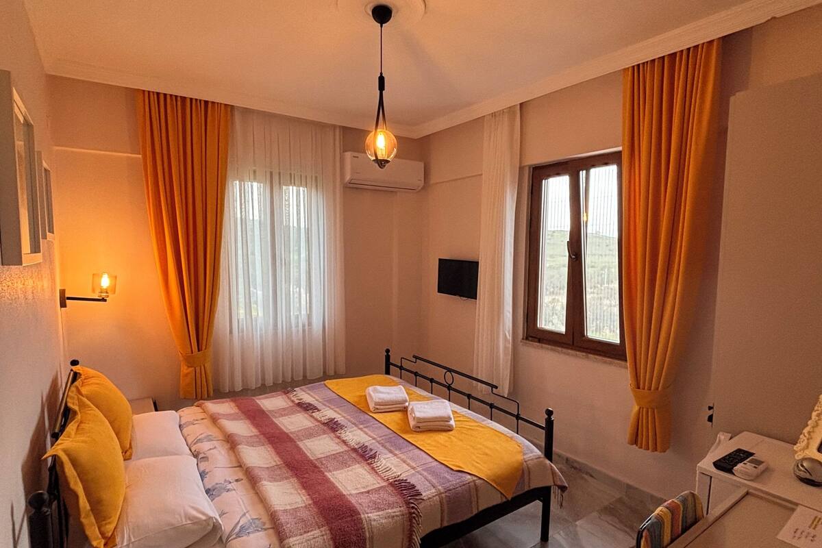 Une chambre à coucher avec un lit, un bureau, une chaise, une lampe et une fenêtre.