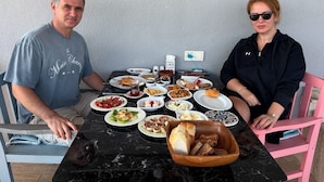 A dining table with various dishes and a bowl of bread. - Zeus kır evi (Bozcaada)