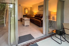 A living room with a brown sofa, a white wicker chair, a small table, and a lamp. - Cozy Condo w/ Pool Access 1 Mi From Siesta Key (Sarasota)