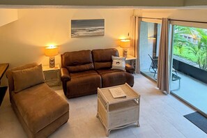 A living room with a brown sofa set, two side tables with lamps, a small white side table, and a view of greenery through the glass door. - Cozy Condo w/ Pool Access 1 Mi From Siesta Key (Sarasota)