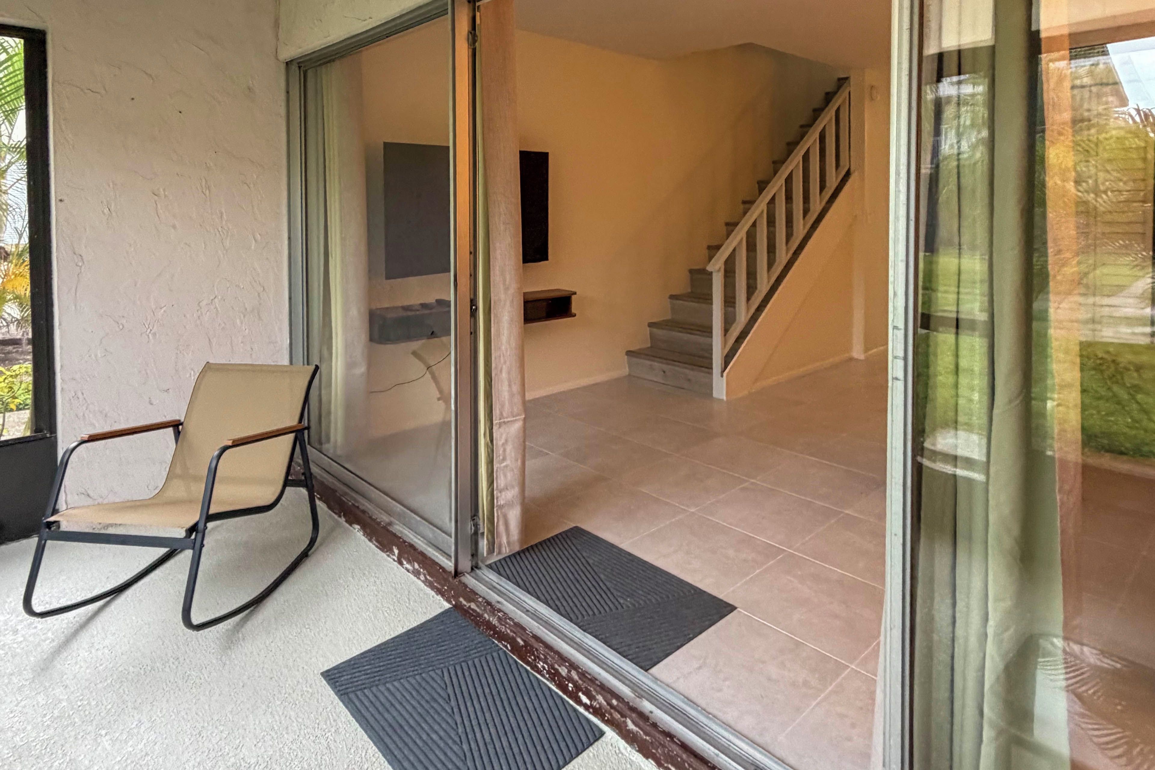 A room with a sliding glass door leading to a staircase, a chair, and a small table.
