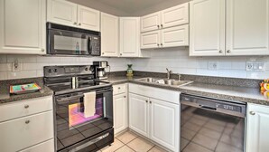 A kitchen with white cabinets, a microwave, an oven, a dishwasher, and a granite countertop. - Condo w/ Pool Access < 4 Miles to Siesta Key Beach (Sarasota)