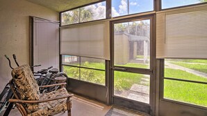 A room with a ceiling fan, large windows with blinds, a bicycle, and a chair.