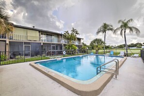 Une piscine d’une profondeur de 2,06 mètres (6 pieds et 9 pouces), entourée d’une clôture, avec un bâtiment et des palmiers en arrière-plan.