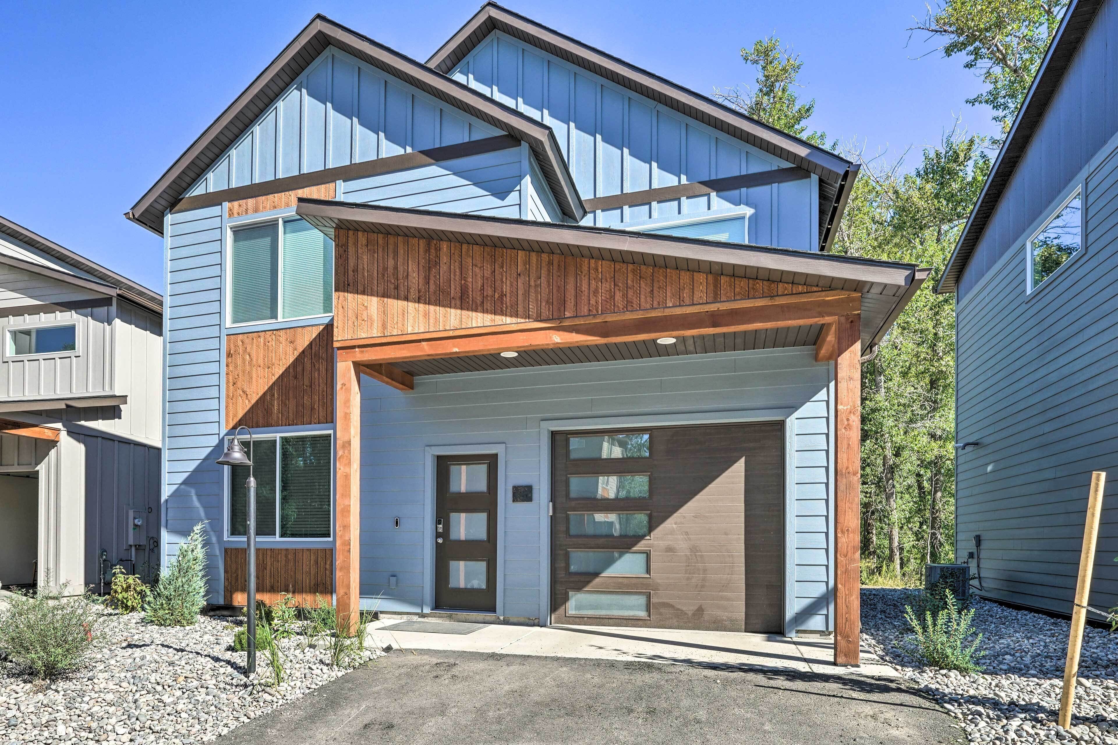 A modern two-story house with a garage, wooden accents, and a clear driveway.