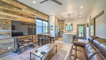 A modern living room with a leather sofa, a wooden coffee table, and a TV on a wooden stand.
