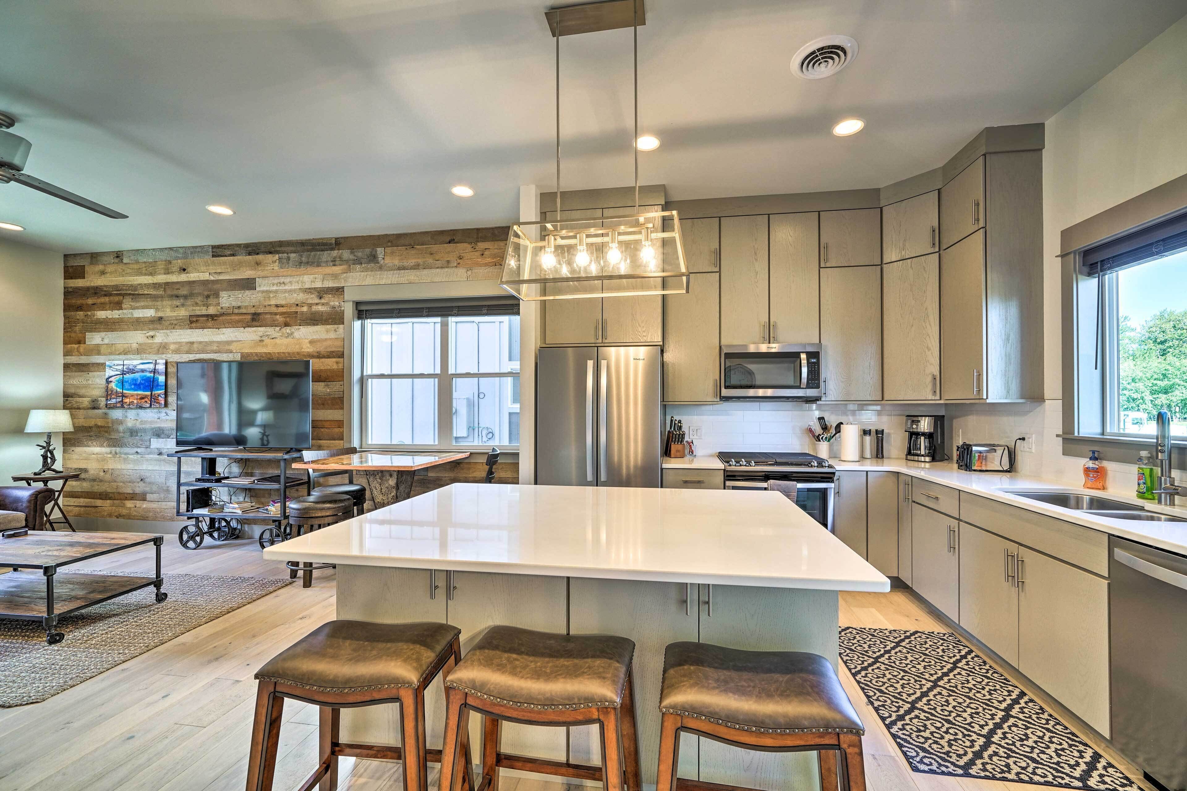 A modern kitchen with a large island, stainless steel appliances, and a rustic wooden accent wall.