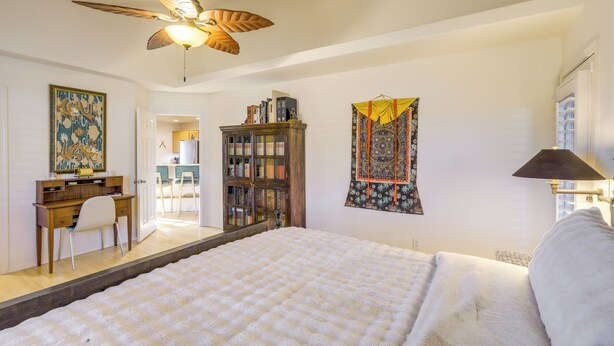 A bedroom with a large bed, a ceiling fan, a desk with a chair, a bookshelf, and a tapestry on the wall. - Game Room + Patios: Home 2 Mi to Dtwn Flagstaff (Flagstaff)