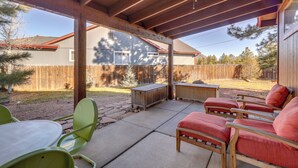 A covered patio area with a wooden ceiling, outdoor furniture, and a view of a backyard with a wooden fence and trees. - Game Room + Patios: Home 2 Mi to Dtwn Flagstaff (Flagstaff)