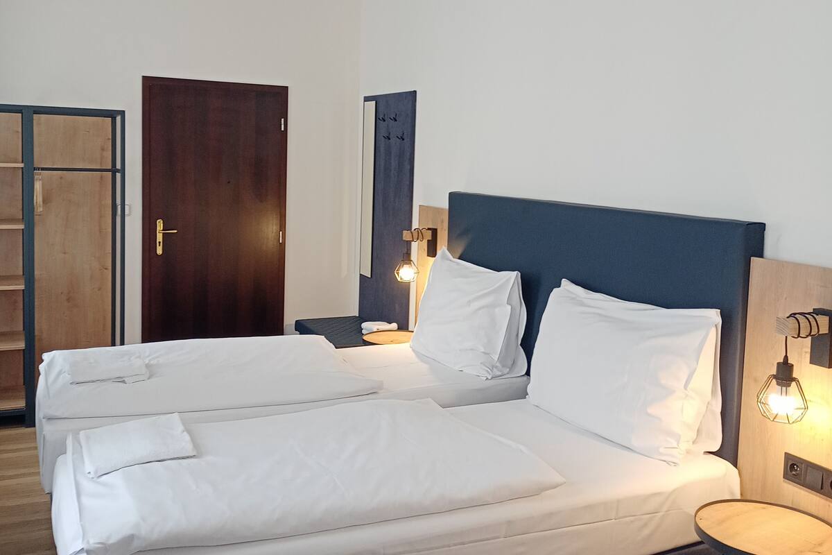 A hotel room with a large bed, bedside tables, a wardrobe, and a mirror.