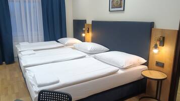 A hotel room with a large bed, two bedside tables, a small round table, a chair, and a wall-mounted clock.