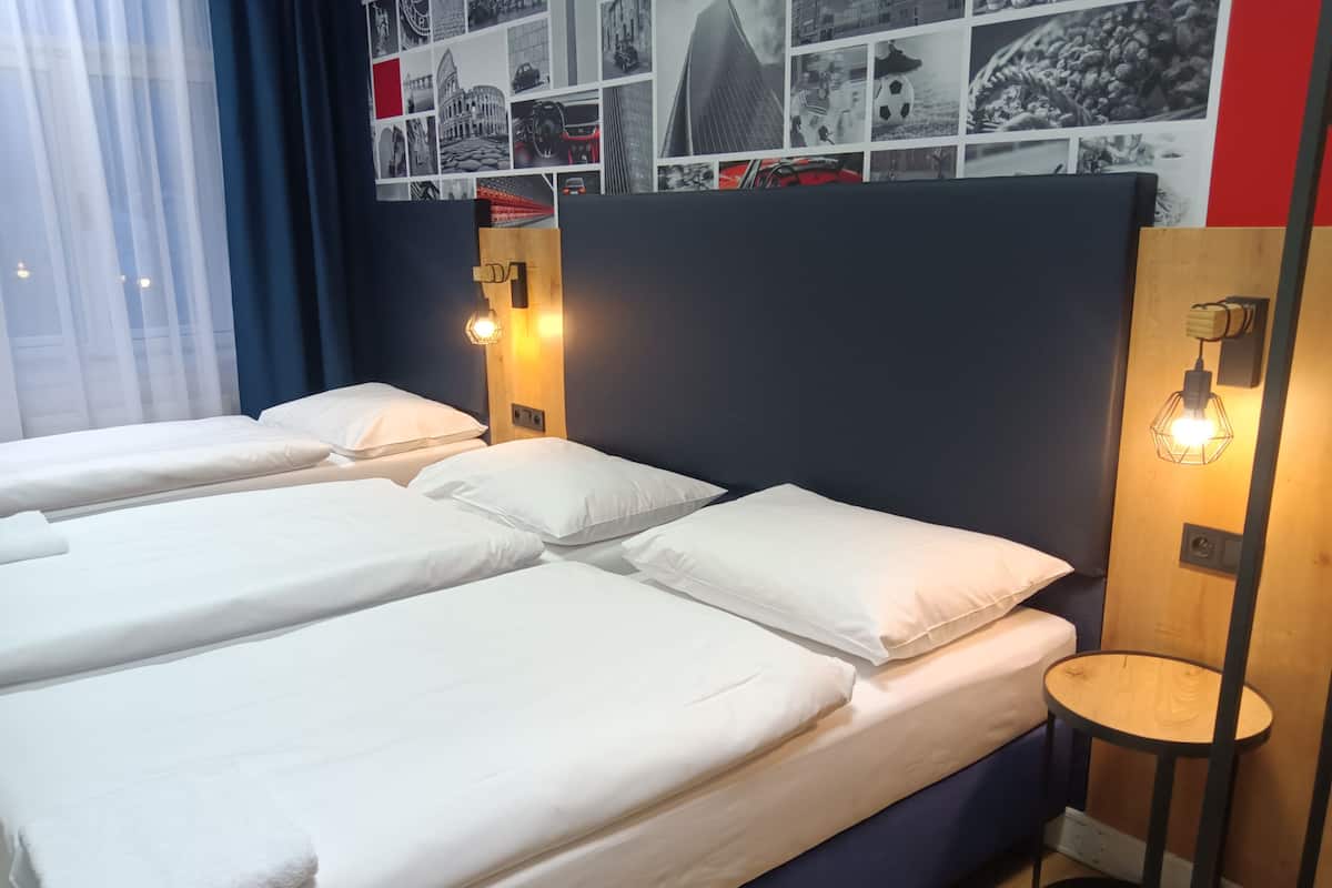 A hotel room with two single beds, a small round table, and a wall decorated with black and white photos.