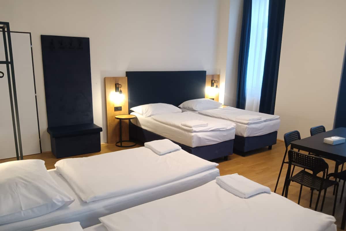 A hotel room with two beds, a small table, and a chair.