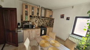 A compact kitchen with wooden cabinets, a microwave, stove, and a dining table with woven placemats.