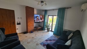 A living room with a brick fireplace, a TV mounted on the wall, a sofa, and a potted plant.