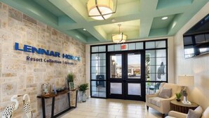 A Lennar Homes Resort Collection lobby with a stone wall, reception desk, and a seating area. - 9 Bedrooms S / Storey Lake Home by RedAwning (Kissimmee)