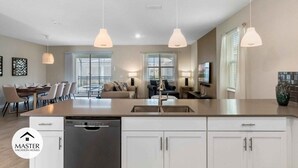 A modern kitchen with a central island, white cabinetry, and pendant lighting. - 9 Bedrooms S / Storey Lake Home by RedAwning (Kissimmee)