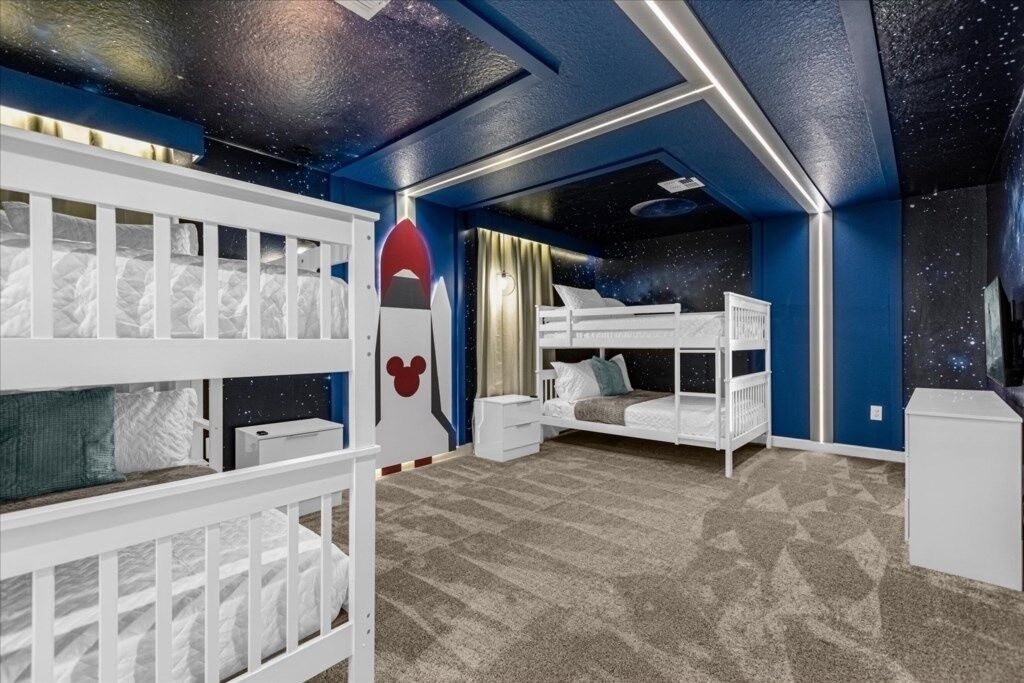 A child's bedroom with bunk beds, a desk, and a starry ceiling design.
