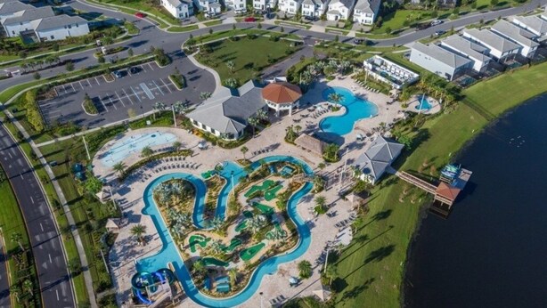 Vue aérienne d’un complexe hôtelier doté de plusieurs piscines, d’un port de plaisance et d’un vaste parking.