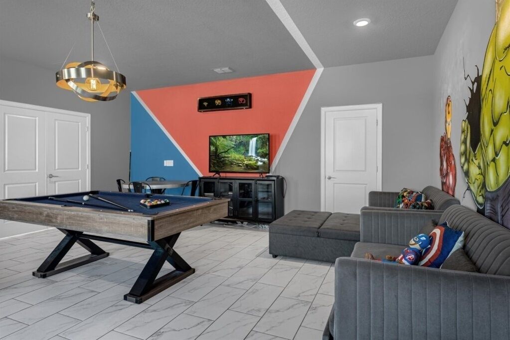 A modern living room with a pool table, a television, and a sofa.