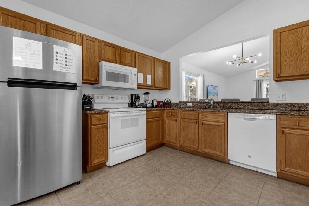 A modern kitchen with wooden cabinets, stainless steel appliances, and a granite countertop.