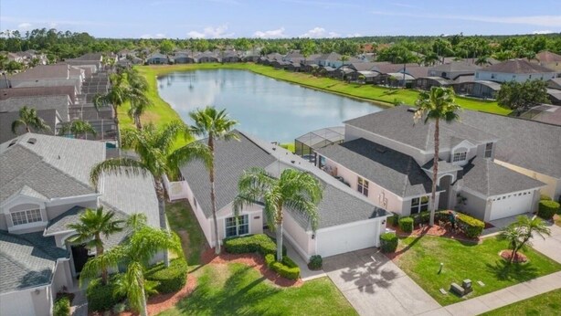 A residential area with houses, a central pond, and palm trees.