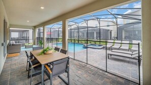 Un patio cubierto con piscina, mobiliario de exterior y zona de comedor con mesa y sillas.