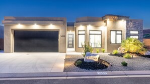 A modern house with a garage, numbered 1459, and a landscaped front yard with plants and a small rock garden.