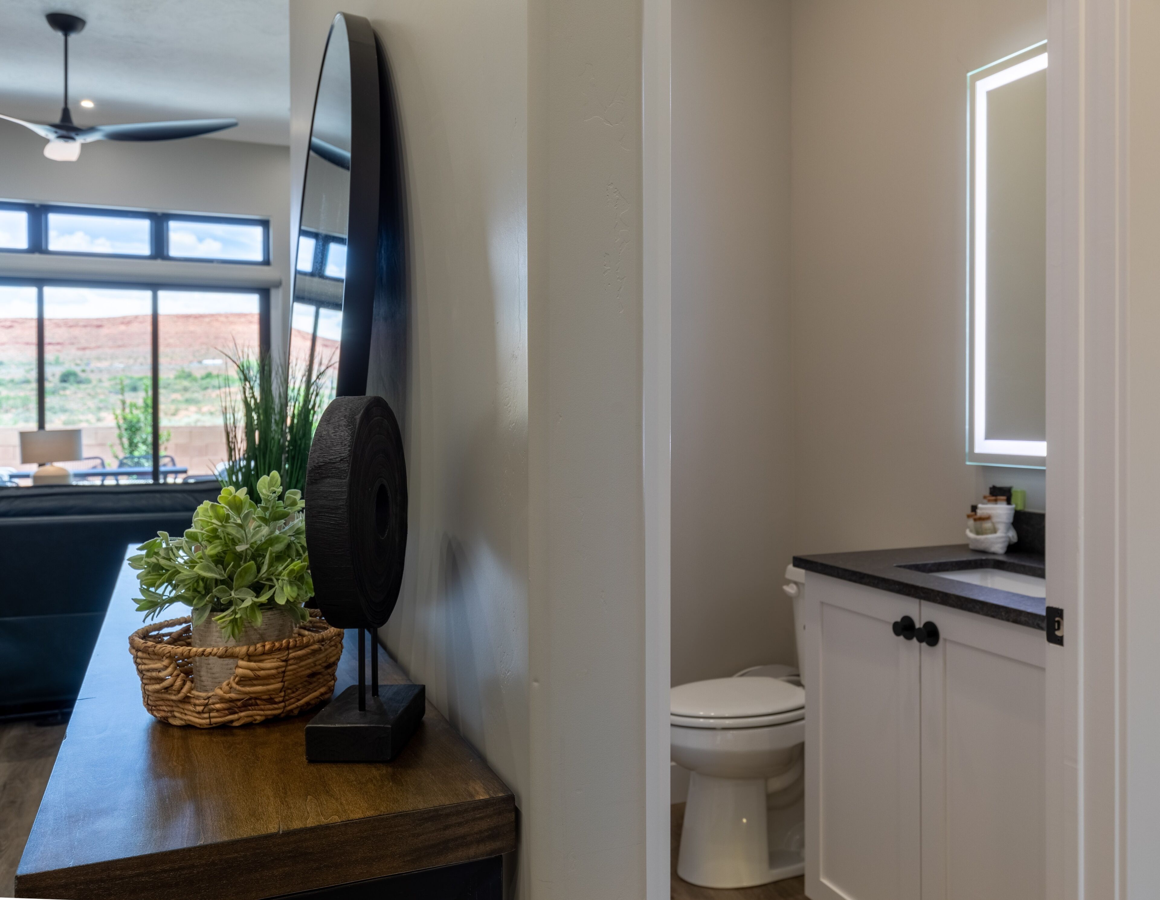 A bathroom with a toilet, a sink, a mirror, and a television mounted on the wall.