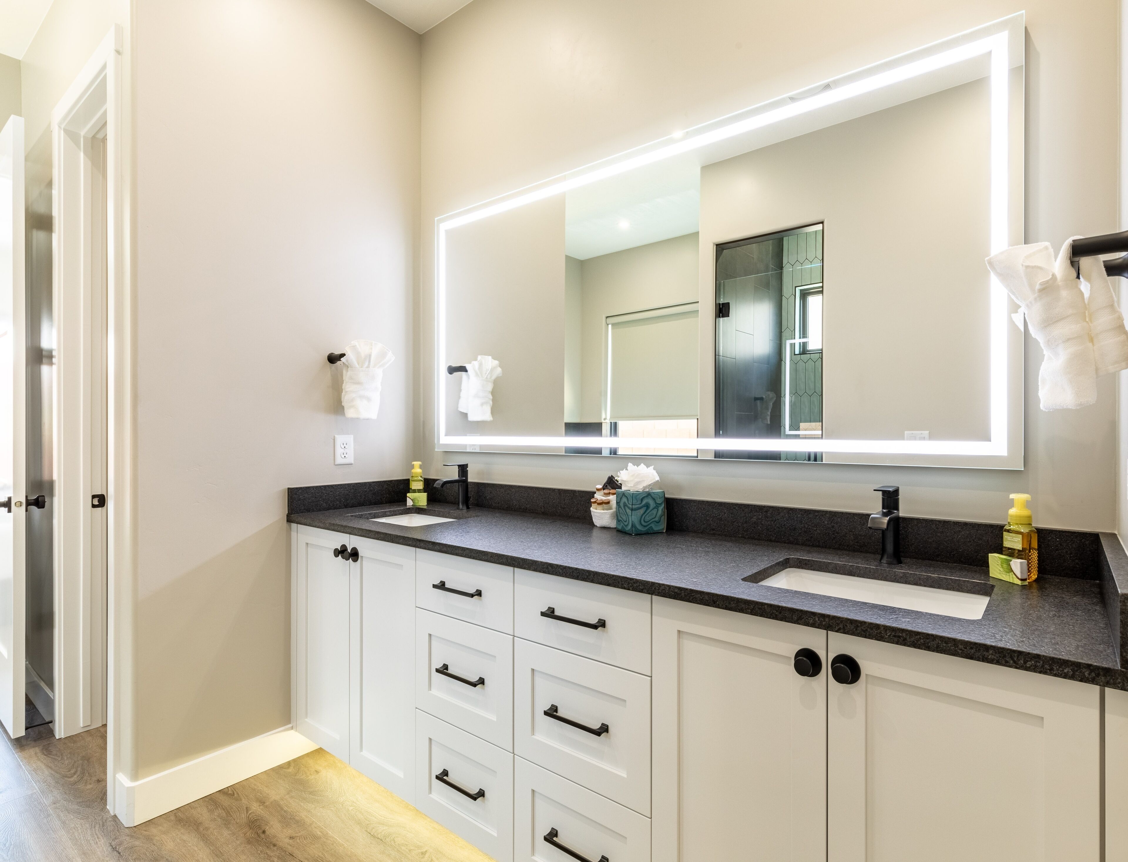 Een moderne badkamer met twee wastafels, een grote spiegel en witte badkamerkasten.